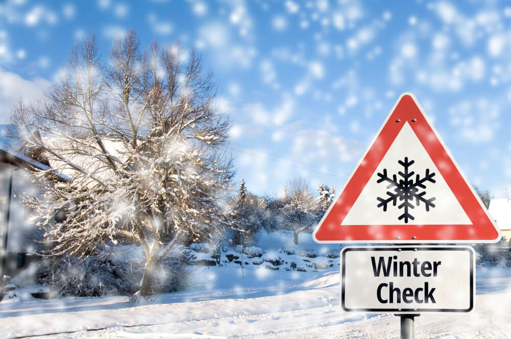 Schneelandschaft mit Winter-Check-Schild und Schneeflocken-Warnsymbol.